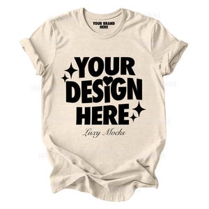 Puede incluir: Una camiseta beige con un gráfico negro que dice "Your Design Here" con un corazón y estrellas. El texto "Luxy Mocks" está debajo del gráfico. El texto "Your Brand Here" está en la etiqueta del cuello.