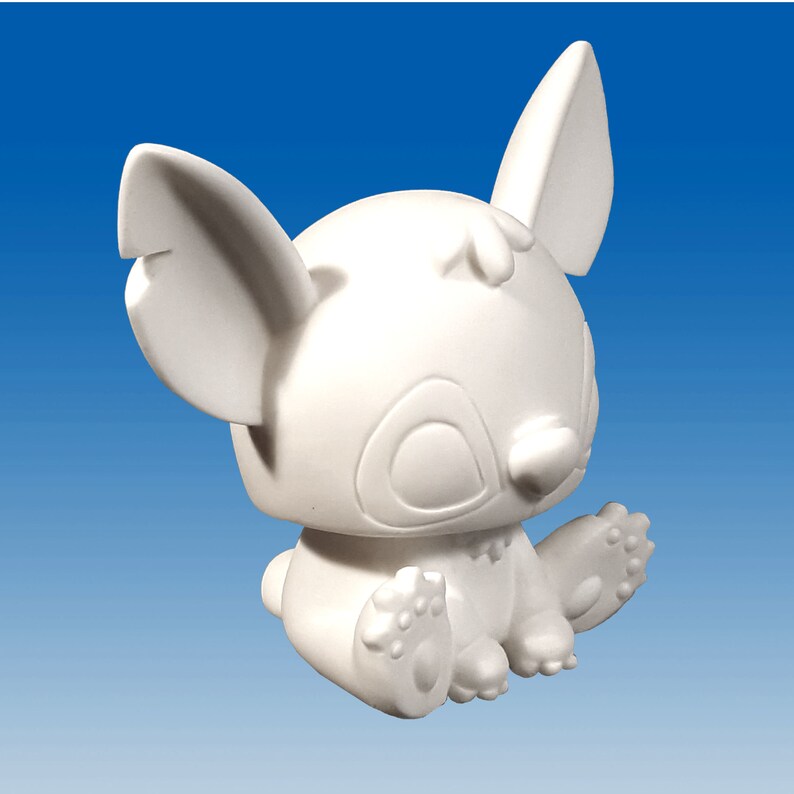 May include: White ceramic figurine of a cartoon character with large ears, sitting with its legs crossed. The character has a round head with large eyes and a small nose.