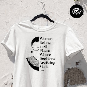 Könnte beinhalten: Weißes T-Shirt mit einer Schwarzweißillustration von Ruth Bader Ginsburg. Der Text lautet "Women Belong In All Places Where Decisions Are Being Made - RBG".