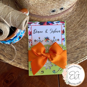 May include: A printable wedding invitation with a colorful Mexican folk art design. The invitation is folded in half and has a bright orange bow on top. The text on the invitation reads "Diane & Joshua".