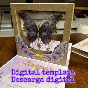 Puede incluir: Un marco de brillo dorado con un inserto de pl&aacute;stico transparente que presenta una mariposa p&uacute;rpura con intrincados detalles dorados. El marco est&aacute; decorado con flores moradas y el texto "Ximena Digital template Descarga digital" es visible debajo del marco.