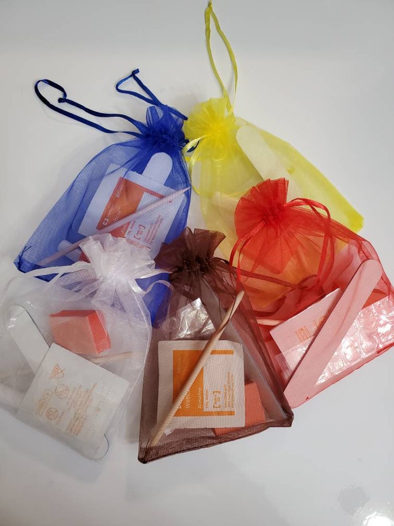 May include: Five small, colorful mesh bags filled with nail care items. The bags are blue, yellow, red, white, and brown. Each bag contains a nail file, buffer, and other manicure tools. The bags are tied with matching ribbons.