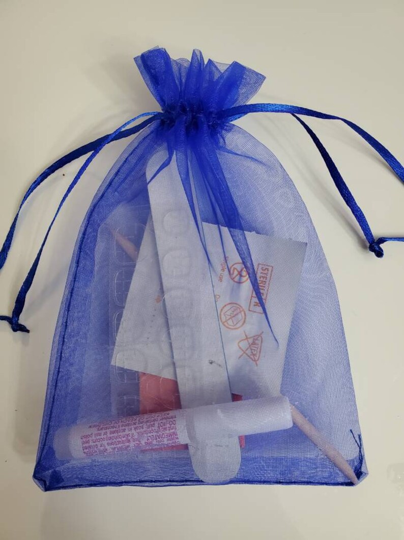 May include: A blue mesh drawstring bag containing nail supplies. The bag is filled with various items, including nail glue, nail stickers, and a nail file. The bag is tied at the top with a matching blue ribbon.
