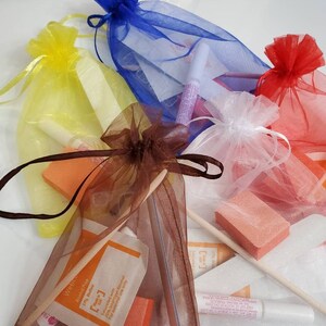 May include: Assortment of nail care kits in colorful organza bags. Each bag, in shades of yellow, blue, red, white, and brown, contains nail files, buffers, glue, and prep pads. The prep pads have the text "Webco Alcohol Prep".