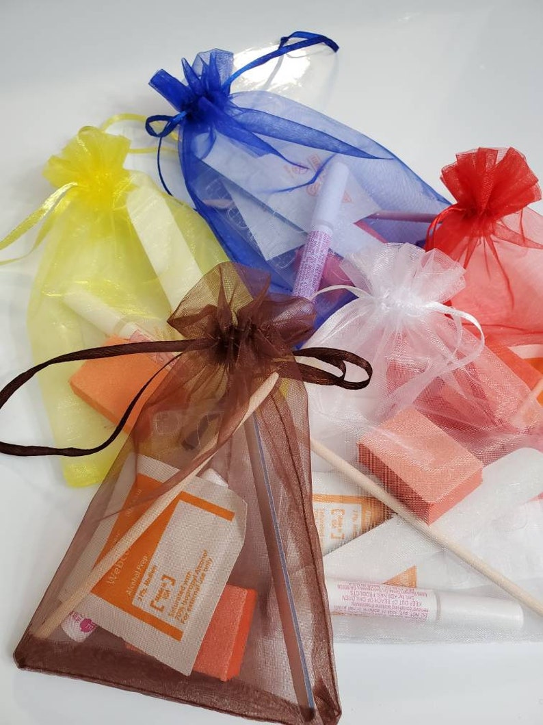 May include: Assortment of nail care kits in colorful organza bags. Each bag, in shades of yellow, blue, red, white, and brown, contains nail files, buffers, glue, and prep pads. The prep pads have the text "Webco Alcohol Prep".