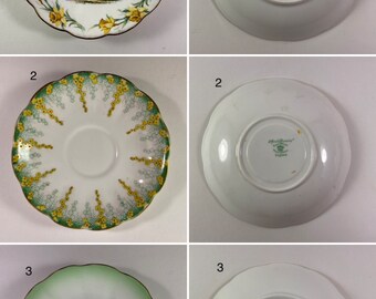 May include: Three sets of Royal Albert teacups and saucers. The first set features a floral design with a castle in the center. The second set features a floral design with green accents. The third set features a green and white ombre design. The back of each saucer features the Royal Albert logo.