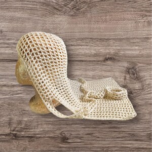 May include: A cream-colored, open-weave crochet hat and matching scarf are displayed on a mannequin head. The hat has a rounded crown and a brim that extends into a strap. The scarf is rectangular with a ruffled edge.