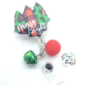 May include: A red and green Christmas tree-shaped badge reel with the words "Merry Bright" printed on it. The reel has a red pom-pom and a green bell charm attached to it.