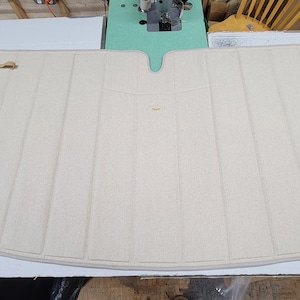 Puede incluir: Una alfombra de suelo beige de moqueta con una abertura en forma de V en el centro y dos correas beige a los lados.