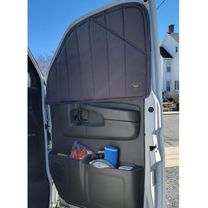 Puede incluir: Una puerta de furgoneta gris con un panel de puerta negro y una pantalla de ventana gris. La pantalla de la ventana tiene un logotipo que dice "REI Co-op". Hay bolsillos de almacenamiento en el panel de la puerta.