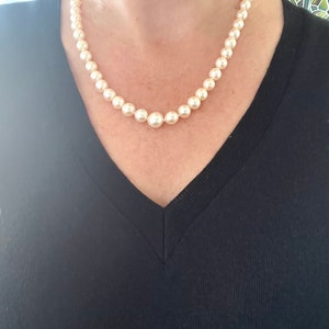 May include: A classic pearl necklace with a simple design. The pearls are white and round, and the necklace is strung on a thin chain.