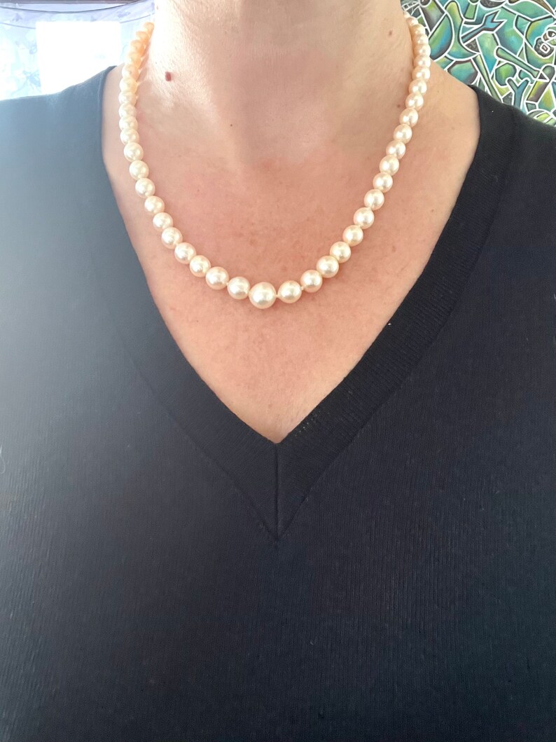 May include: A classic pearl necklace with a simple design. The pearls are white and round, and the necklace is strung on a thin chain.