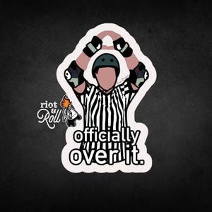 May include: A black and white striped referee shirt with a black and white striped referee whistle. The referee is making the "over it" gesture with their hands. The text "officially over it" is below the referee. The text "riot & roll" is in the top left corner of the image.