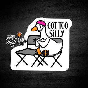 Puede incluir: Una pegatina blanca con un ganso de dibujos animados con un casco rosa y patines, sentado en una silla plegable. El texto "GOT TOO SILLY" está encima del ganso. La pegatina también incluye el logotipo "riot & Roll".