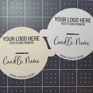 Another photo of two custom candle dust cover examples - one in cream, one in white, both with wood wicks and basic sample text on top of a measuring grid for size.