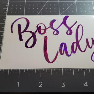Photo featuring two examples of the Boss Lady vinyl decal - purple holographic sparkle in 5-inches - on a gray measuring mat for size.