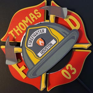 May include: Red, yellow, and black firefighter themed cake topper with the name "THOMAS" and the number "03" on it. The topper also features a firefighter helmet with the words "FIREFIGHTER" and "HOUSTON" on it.