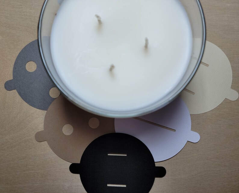Overview of candle dust covers in a variety of color options, including black, white, cream, gray, and kraft brown. A silver tin candle is featured with a black dust cover in standard wick as an example.