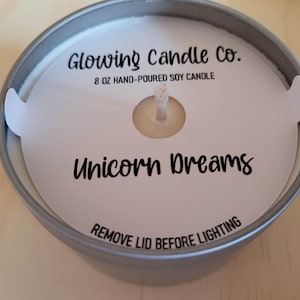Photo featuring a sample of custom candle dust covers with mockup candle company name, candle ounces and type of wax, scent name Unicorn Dreams and the standard remove lid before lighting text at the bottom. White cardstock black ink standard wick.