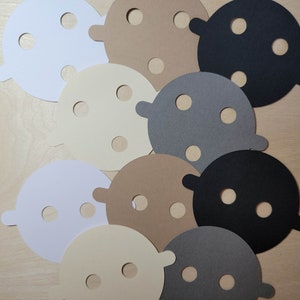 Overhead view of candle dust covers in black, gray, white, and cream on a wood background. Standard and wood wick options.