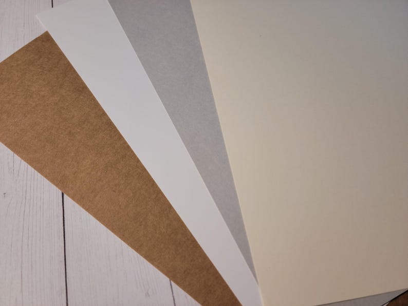 Photo showing the new and old versions of the kraft cover stock materials used for making custom candle dust covers. The newer version is a couple of shades darker and is actually more of a "true" kraft color.