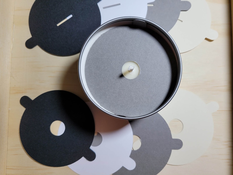 Overview of candle dust covers in a variety of color options, including black, white, cream, gray, and kraft brown. A silver tin candle with a gray dust cover in standard wick is featured.