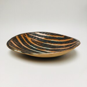 May include: A ceramic serving bowl with a brown and white striped pattern. The bowl is oval shaped and has a slightly raised rim.