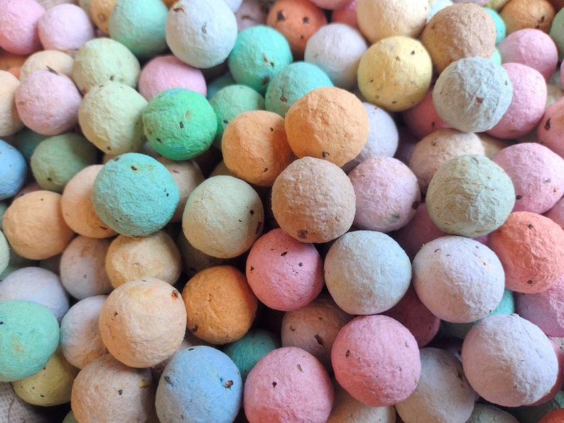 May include: A close-up of a collection of colorful paper balls. The balls are made of recycled paper and are available in a variety of colors, including pink, blue, green, and yellow.