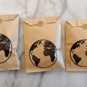 May include: Three brown paper bags with a black globe design and a brown circle sticker on the top.