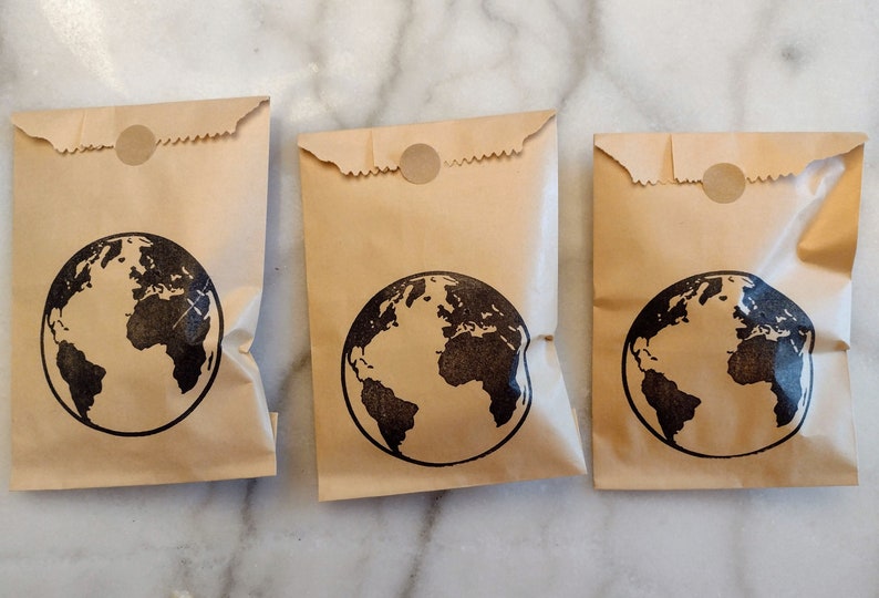 May include: Three brown paper bags with a black globe design and a brown circle sticker on the top.