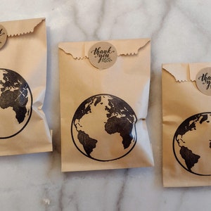 May include: Three brown paper bags with a black globe design and a round brown sticker that says "Thank you".