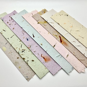 May include: A set of ten handmade paper sheets in various pastel colors with embedded natural fibers. The paper has a textured, handmade look and feel.