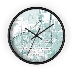 Peut inclure: Une carte de Springfield, Illinois en noir et blanc avec un c&oelig;ur rouge marquant un emplacement. La carte est sur une horloge ronde avec des aiguilles noires et un cadre noir. Le texte "RICHARD & TANYA DUFFEY Springfield, Illinois 1st Wedding Anniversary 4:00 PM. 09-04-2021" est imprim&eacute; sous la carte.