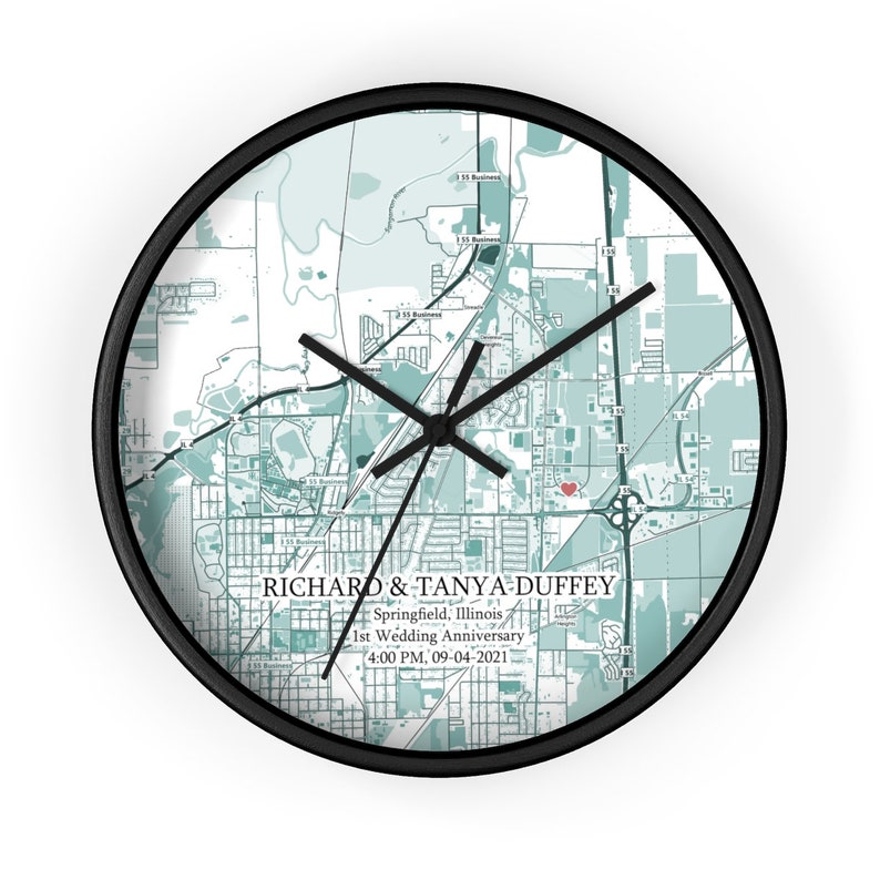 Peut inclure: Une carte de Springfield, Illinois en noir et blanc avec un c&oelig;ur rouge marquant un emplacement. La carte est sur une horloge ronde avec des aiguilles noires et un cadre noir. Le texte "RICHARD & TANYA DUFFEY Springfield, Illinois 1st Wedding Anniversary 4:00 PM. 09-04-2021" est imprim&eacute; sous la carte.