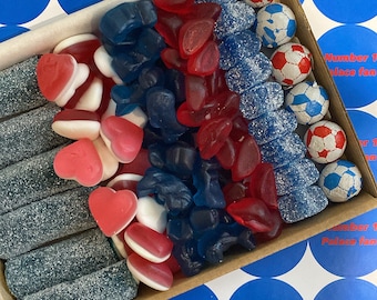 May include: A box filled with blue, red, and white candies. The candies are shaped like hearts, fish, and soccer balls. The box is lined with blue and white paper with the text "Number 1 Palace fan!" repeated on the sides.