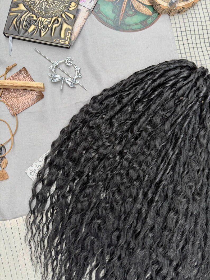 May include: A bundle of long, black synthetic hair extensions with a wavy, textured finish. The hair strands are tightly coiled and layered, creating a voluminous appearance. The dark black color is consistent throughout the entire length of the hair.