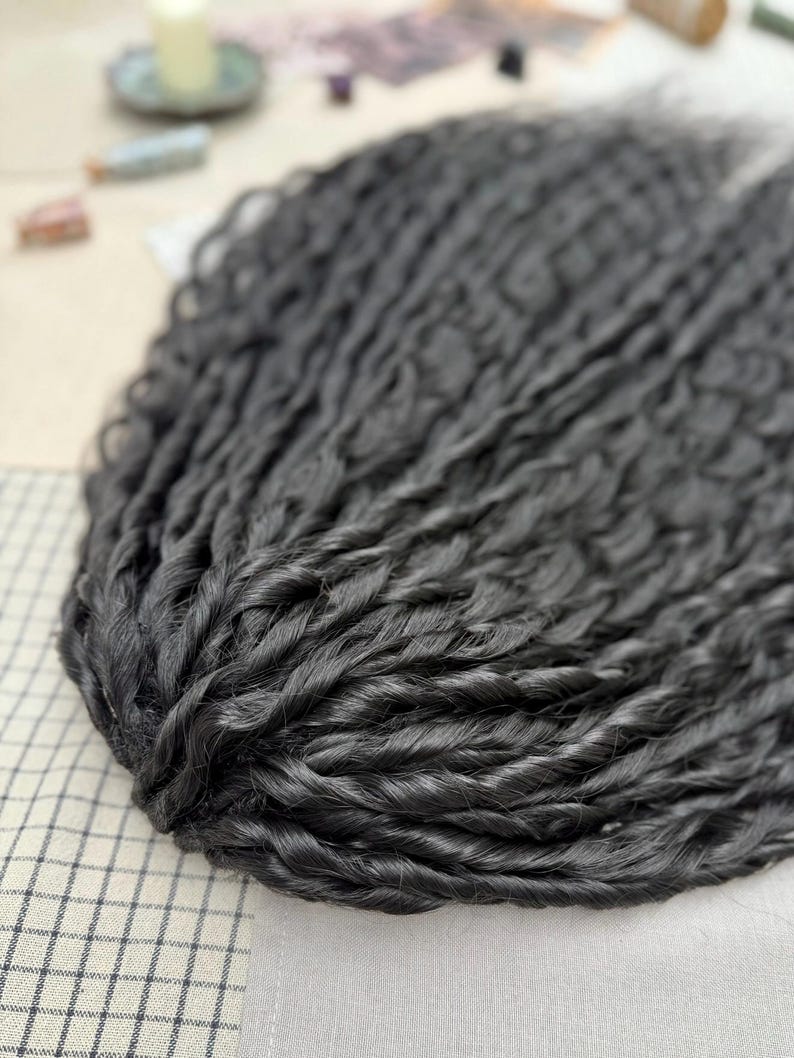 May include: A bundle of long, dark charcoal-black hair extensions featuring a tight, twisted, and wavy texture. The individual strands are densely packed together, creating a voluminous and uniform appearance with a consistent dark color throughout.