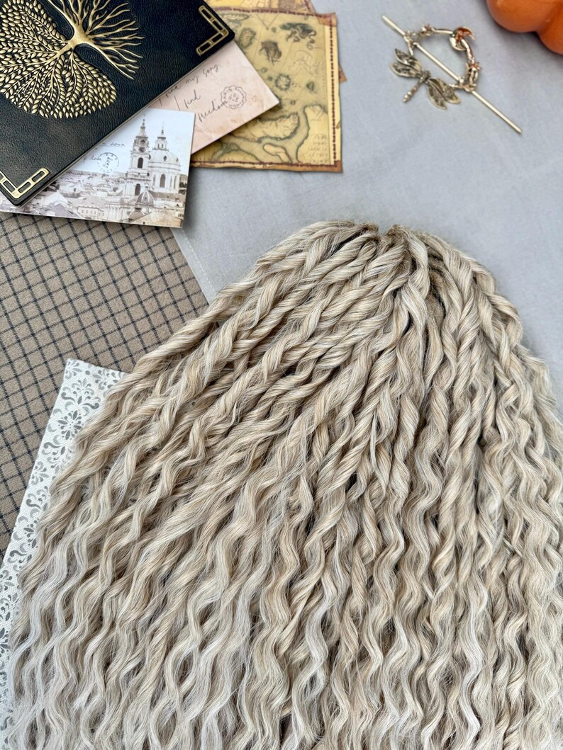 Pu&ograve; includere: Un set di extension per capelli sintetici biondo chiaro caratterizzato da una consistenza stretta, ondulata e ritorta. Le ciocche sono disposte in un fascio denso e uniforme, mostrando una tavolozza di colori biondi con sottili variazioni.