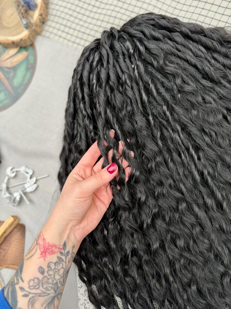 May include: A set of long, black synthetic hair extensions styled in tight, uniform twists. The hair features a consistent, wavy texture throughout each individual strand, creating a voluminous and layered appearance with a deep, dark black color.