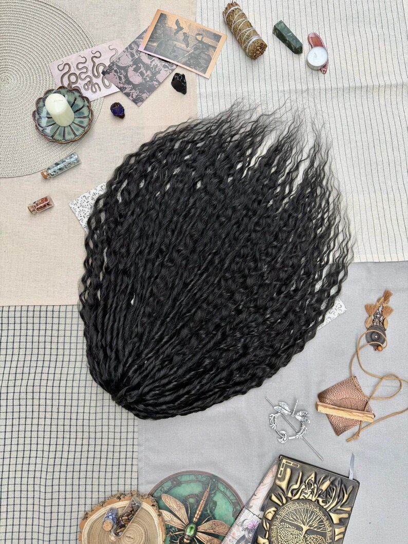 May include: A bundle of long, black, wavy hair extensions with a crimped texture. The hair is arranged in a fan shape, showcasing the dark color and the consistent, tight wave pattern throughout the length of the individual strands.