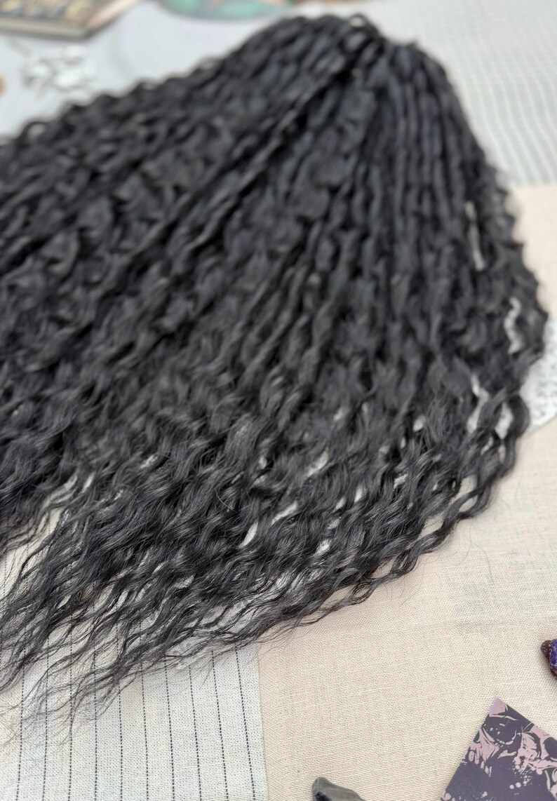 May include: A bundle of long, black hair extensions featuring a deeply wavy, crimped texture. The strands are dark, uniform in color, and arranged in a dense, flowing cluster that highlights the intricate, repetitive wave pattern throughout the length.