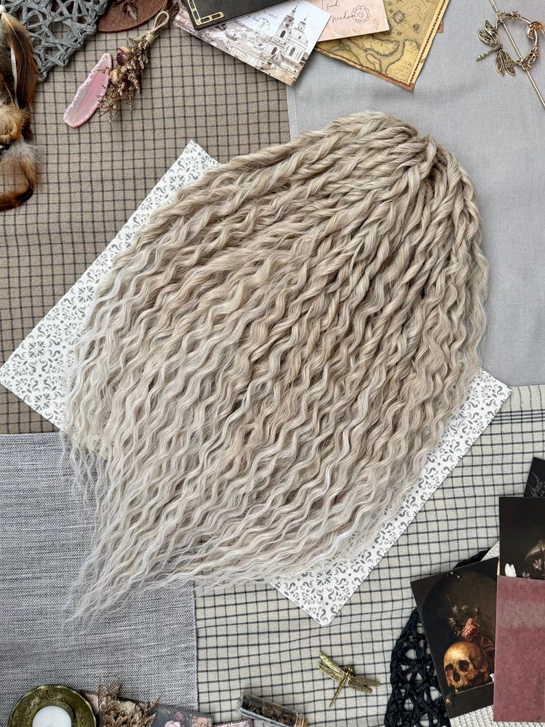Pu&ograve; includere: Un set di extension per capelli biondo chiaro caratterizzato da una consistenza ondulata e crespa. Le ciocche sono disposte in un gruppo denso e stratificato, mostrando un colore pallido e cenere uniforme lungo tutta la lunghezza dei pezzi.