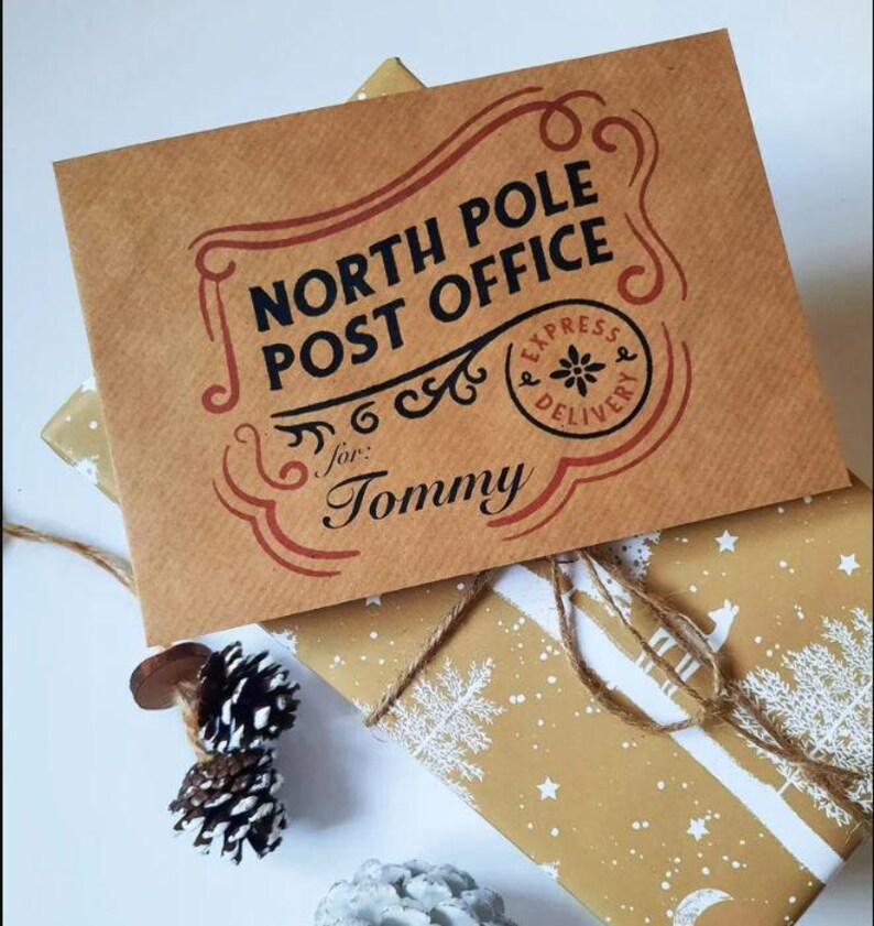May include: A brown paper envelope with the text "North Pole Post Office" in black lettering. The envelope has a red border and a red stamp that says "Express Delivery" with a snowflake in the center. The envelope is addressed to "Tommy".