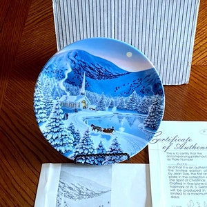 May include: A decorative plate with a winter scene, featuring a church, horse-drawn carriage, and snow-covered landscape. The plate is accompanied by a certificate of authenticity and a box with the "W.S. George" logo. The plate is part of the "Silent Night" series.