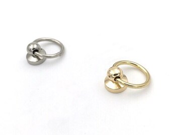 May include: Two metal rings with a ball on top. The ring on the left is silver and the ring on the right is gold.