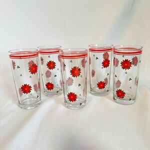 May include: Set of six clear glass drinking glasses with a red and white stripe around the top and a pattern of red poinsettia flowers and green holly leaves.