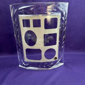 May include: A white ceramic mug with a black handle and the text "But First, Coffee" in a bold, black font. The mug sits on a white surface, showcasing its clean design.