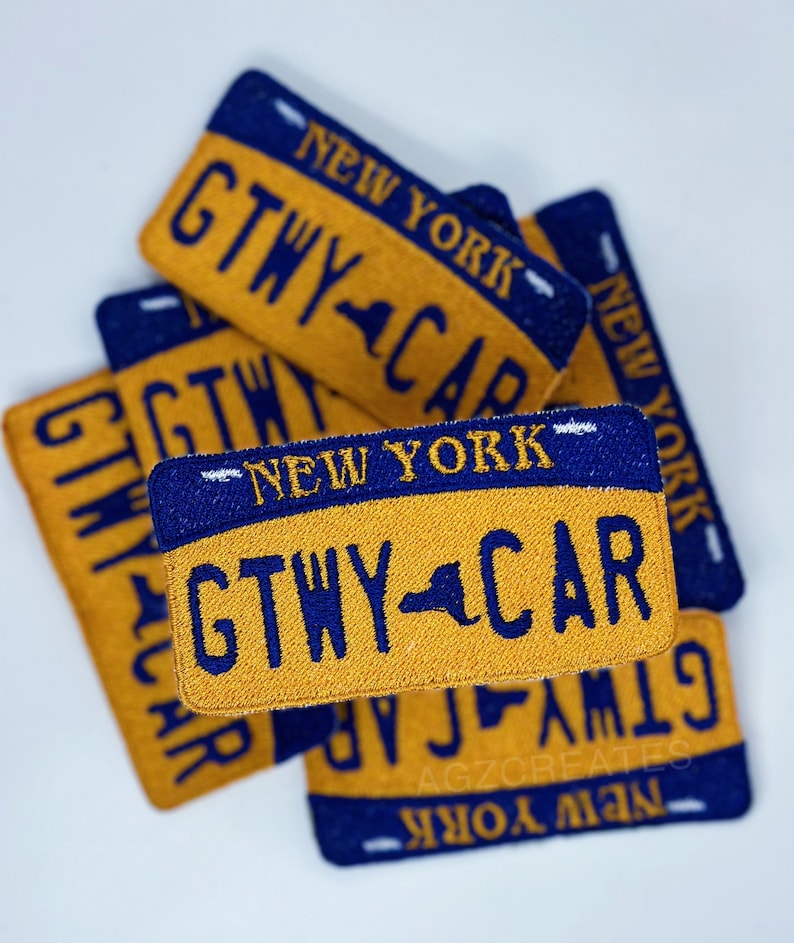 K&ouml;nnte beinhalten: Ein Stapel von vier gestickten Patches in Gelb und Blau mit dem Text "NEW YORK" und "GTWY CAR". Die Patches haben die Form eines Nummernschilds.