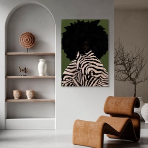 Op de afbeelding: Een kunstafdruk met een persoon met een grote afro en een jas met zebraprint tegen een groene achtergrond. Het kunstwerk wordt getoond in een modern interieur met een bruine leren stoel en decoratieve planken.