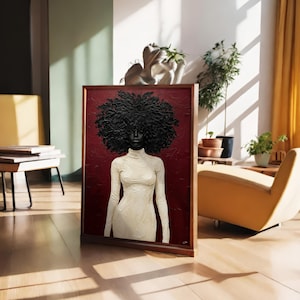 May include: A framed artwork featuring a portrait of a person with a large, textured black afro and a white turtleneck dress against a deep red background. The artwork is displayed in a well-lit room with a wooden floor.